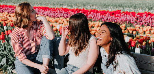 Three women laughing in a flower field