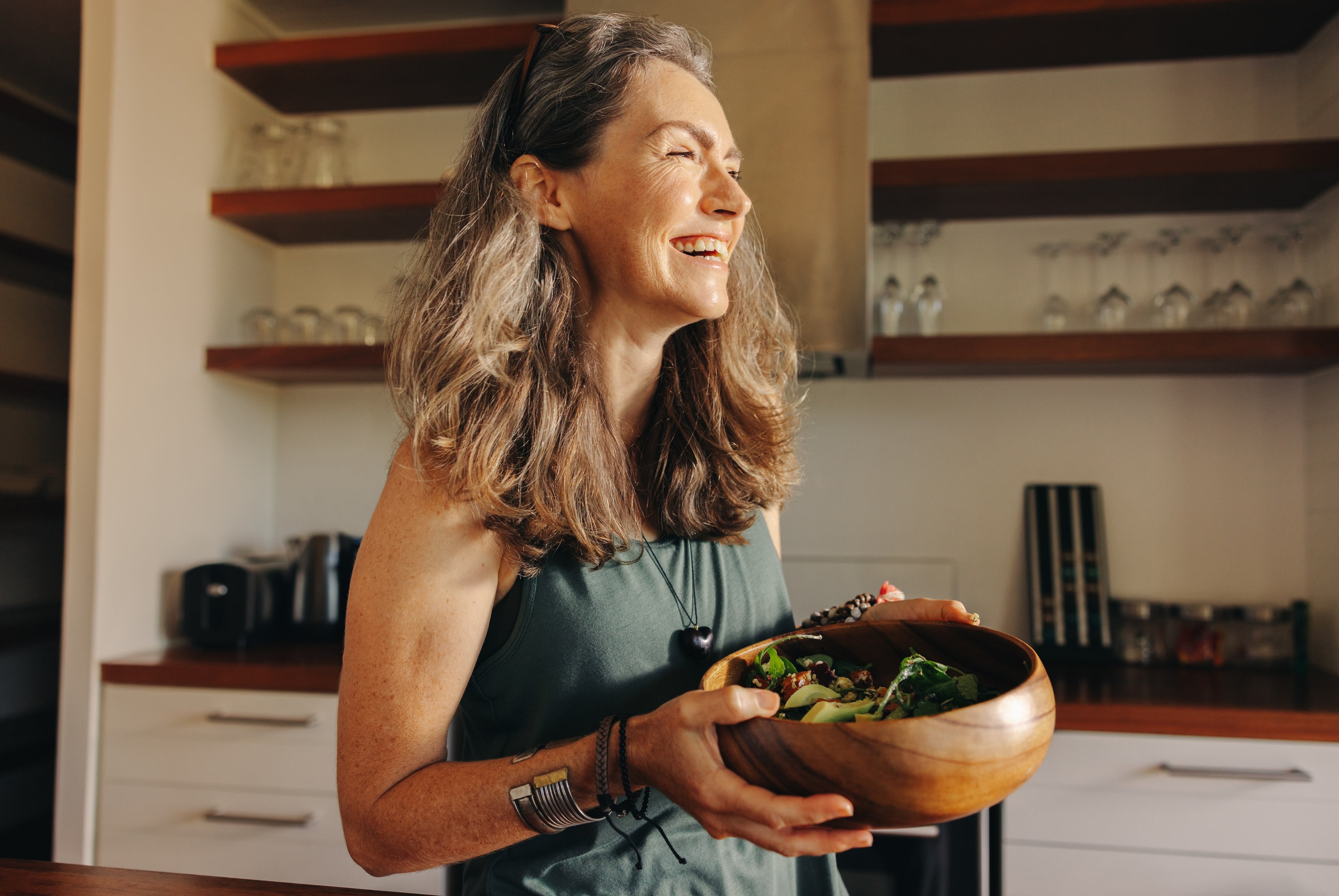 Woman smiling holding healthy food bowl getting her essential women's vitamins